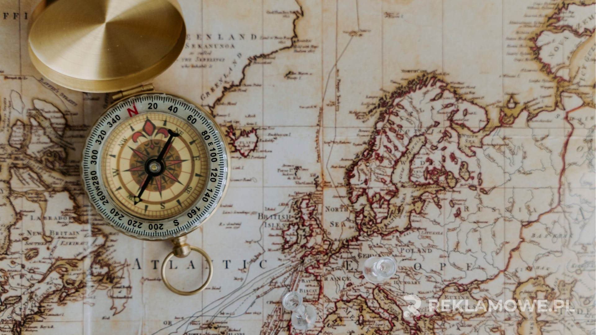 Kompas leżący na mapie z logo marki